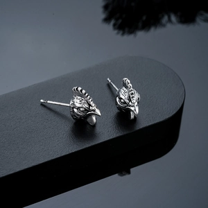 Detailed view of vintage silver rooster stud earrings with intricate feather carvings