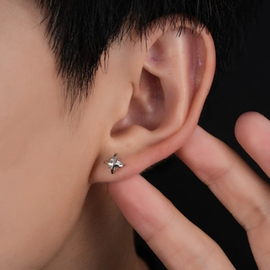 Minimalist silver cross star stud earring with center zircon stone on a male model