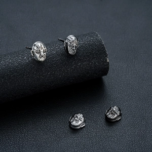 Retro Chinese opera mask stud earrings with vintage silver finish on black pedestal