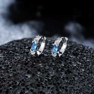 Vue macro de boucles d'oreilles en zircon bleu sur pierre volcanique noire