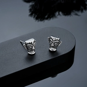 Macro detail of retro silver Sanxingdui mask earrings featuring intricate bronze textures