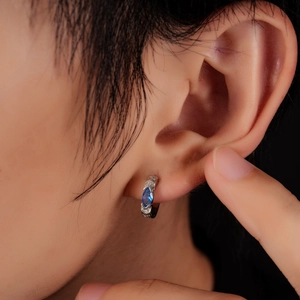 Gros plan d'une boucle d'oreille en argent avec zircon bleu et diamants blancs