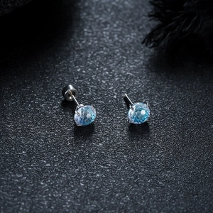 Macro detail of four-prong gradient blue crystal earrings on black leather background