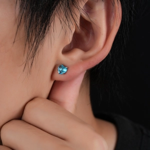 Nahaufnahme eines herzförmigen blauen Zirkonia-Ohrrings mit silberner Krappenfassung