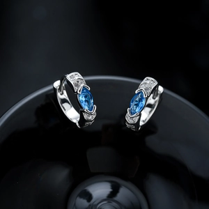 Détail des boucles d'oreilles argentées avec zircon bleu marquise et pierres blanches