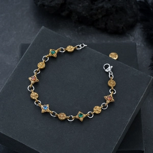 Gros plan du bracelet vintage doré avec pierres multicolores et maillons ajourés fleuris