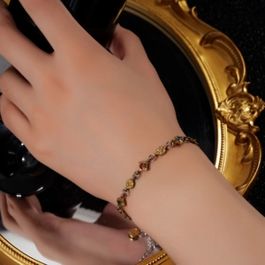 Vue détaillée du bracelet rétro doré avec gemmes colorées et maillons en étoile au poignet