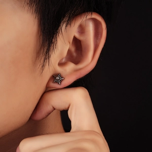 Macro shot of punk style star stud earring with vintage finish on human ear