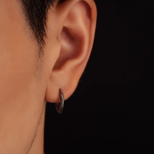 Detailed close-up of textured gunmetal triangle earrings on ear with black background