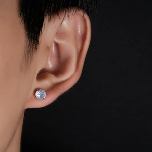 Macro view of a single round-cut cubic zirconia stud earring on a model's ear