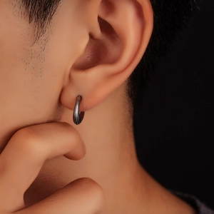 Macro shot of silver titanium steel hoop earring with parallel textured lines