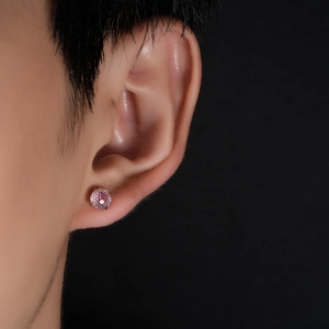 Detail of pink round brilliant cut gemstone earring on male model with four-claw setting