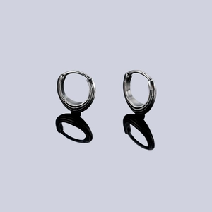 Symmetric silver triangle huggie earrings with vertical stripes on a black mirror surface