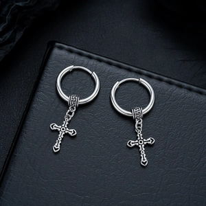 Macro view of vintage silver cross pendant earrings with ornate gothic texture