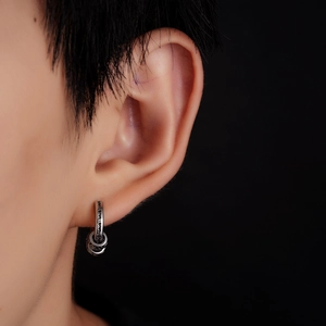 Detailed close-up of vintage silver hoop earring with engraved wave patterns and small rings
