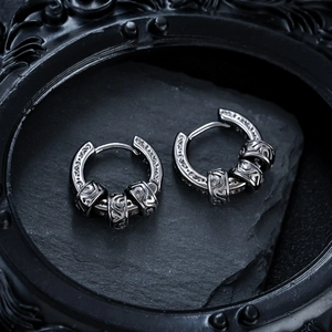 Detailed close-up of vintage hoop earrings with engraved scroll patterns on black stone