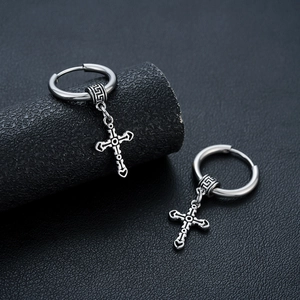 Silver cross hoop earrings with engraved industrial details on a black texture background