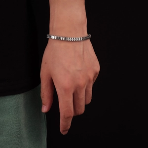 Close-up of silver titanium steel fish scale bracelet worn on wrist with black background