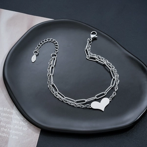 Double-layered stainless steel heart bracelet with paperclip chain on a black tray