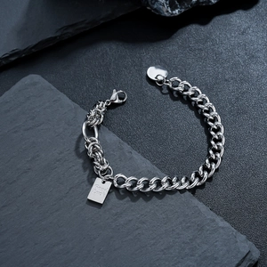 Bracciale a catena argentata con ciondolo Good Luck su sfondo di pietra scura