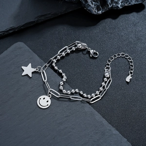 Macro detail of silver layered bracelet with star charms and smiley face pendant