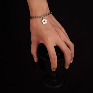 Silver stainless steel chain bracelet with white flower pendant worn on model's wrist
