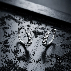 Polished silver twisted rope hoop earrings displayed on a textured dark stone background