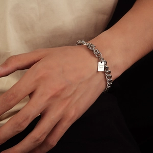 Dettaglio del bracciale a catena argento con piastrina incisa Good Luck sul polso