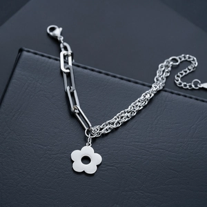 Detailed close-up of polished silver flower pendant on asymmetric chain bracelet