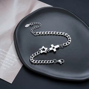 Detail of silver Cuban link bracelet with star and cross charms on a black tray
