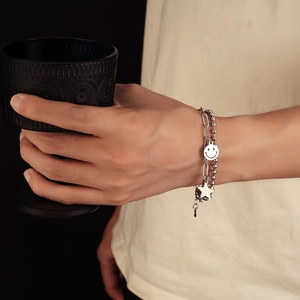 Silver double layer bracelet with smiley face and star charms on a stylish model hand