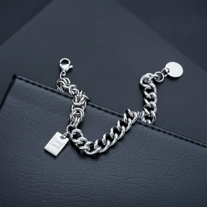 Dettaglio del bracciale a catena argento con targhetta Good Luck e ciondolo tondo