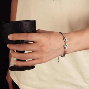 Silver-tone cross and star charm bracelet for men and women on a casual wrist