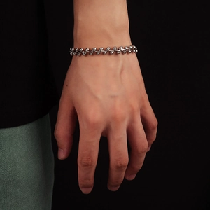 Dettaglio del bracciale a catena con sfere in argento lucido indossato dal modello