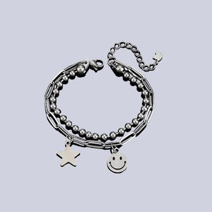 Double-layered silver bracelet with smiley face and star pendants on a modern paperclip chain