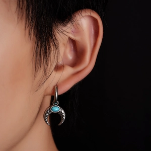 Close-up of bohemian silver crescent earrings with turquoise stone and Celtic engraving