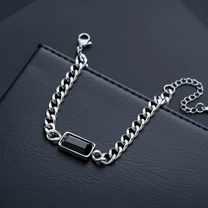 Detail of silver cuban chain bracelet featuring a sleek black rectangular gemstone inlay
