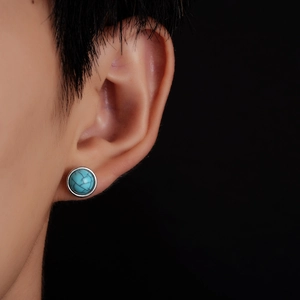 Retro round turquoise stud earring with silver base shown on ear with black background
