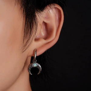 Close-up of bohemian crescent moon earring with turquoise opal inlay and ethnic patterns