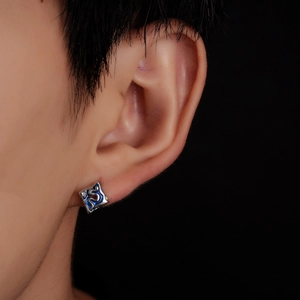 Gros plan d'un clou d'oreille carré en argent avec émail bleu fluide sur l'oreille