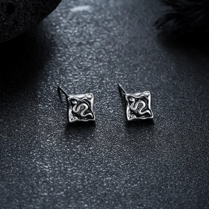 Gros plan de boucles d'oreilles carrées en argent avec texture lave et relief en 3D