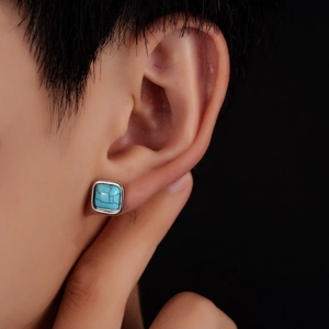 Close-up of square turquoise stud earring with vintage silver setting on model ear
