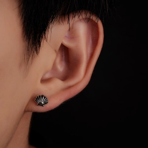 Close-up of a vintage silver seashell stud earring worn on model against black background