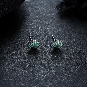 Detailed view of seashell-shaped stud earrings with green enamel and silver-tone finish