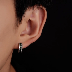 Boucle d'oreille huggie en argent avec zircons verts et blancs sur modèle masculin