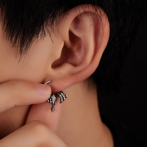 Macro shot of silver scorpion claw earring with white zircon on a black background