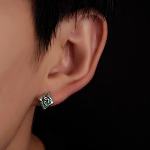 Vue macro de la boucle d'oreille carrée argentée avec émail vert et motif serpent