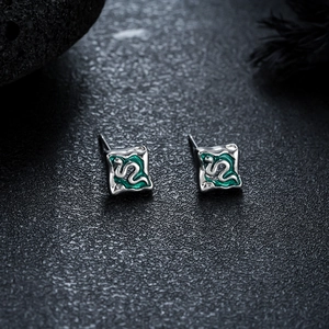 Détail macro de boucles d'oreilles carrées argentées avec motif serpent en émail vert