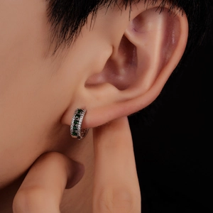 Détail d'une boucle d'oreille en argent avec cinq zircons verts et pavé de diamants