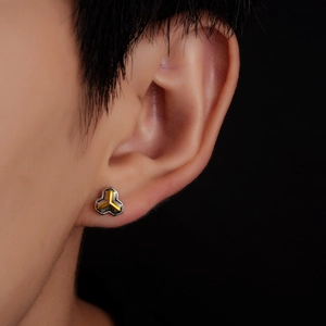 Close-up of geometric clover stud earring with dual-tone gold and matte black finish